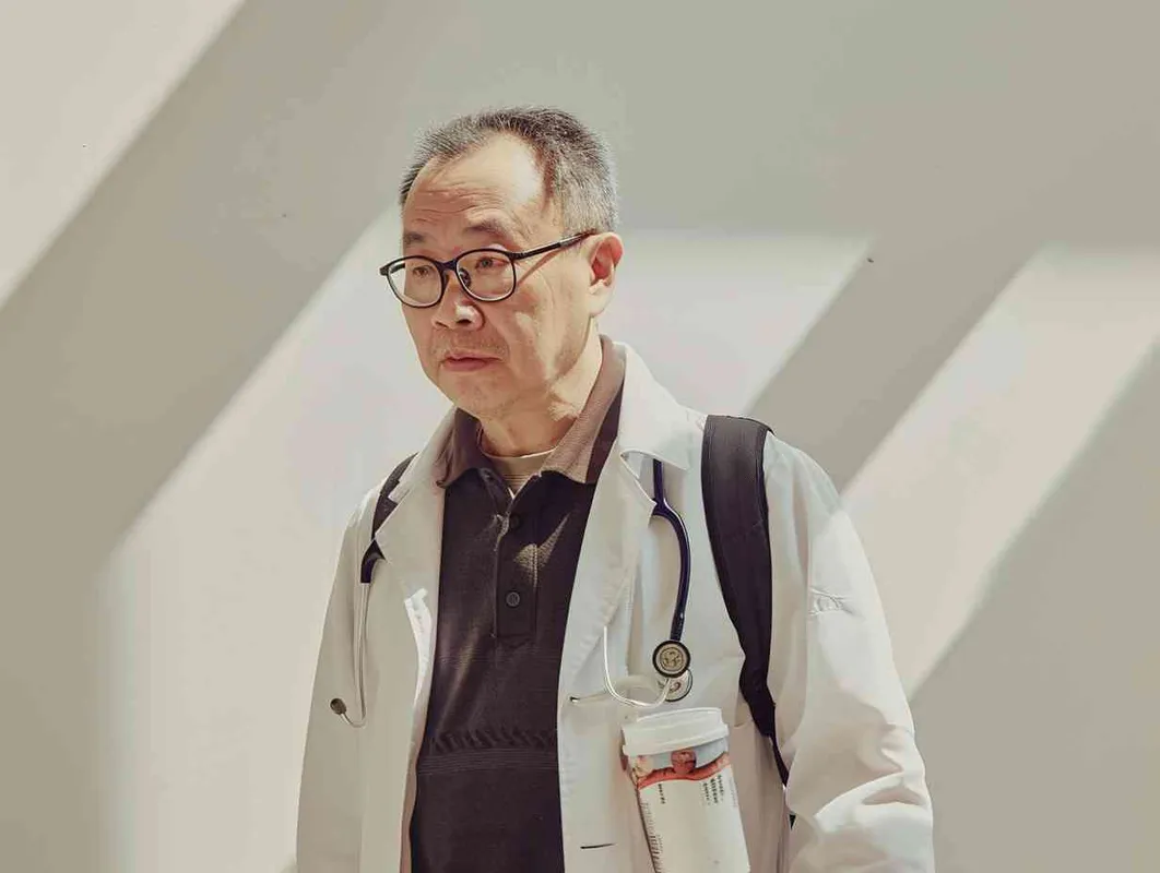 70岁，中国面孔，男，穿着白大褂，手持保温杯，听诊器，戴眼镜，慢慢地走，医院门诊，现代环境，真实，沧桑，疲惫，慈祥，和蔼，温柔 - style2部分