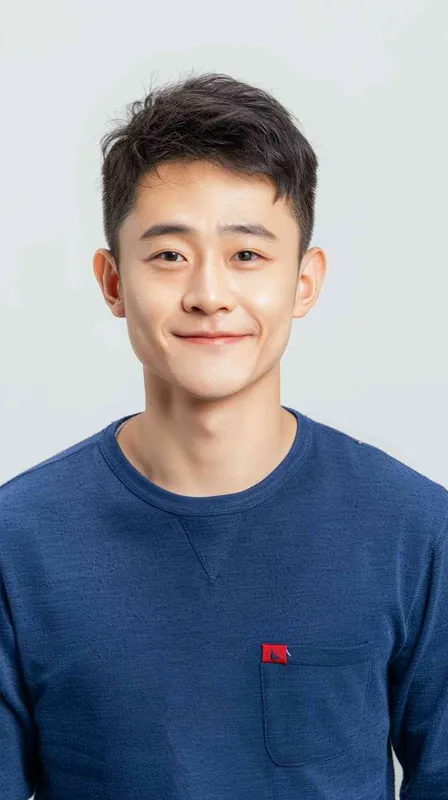 A young Chinese man with short black hair, wearing a blue long-sleeved shirt with a red pocket on the chest area of his right hand is smiling at the camera. The background color should be white to highlight his face. He has an Asian nose shape, medium skin tone, round eyes, and thin eyebrows. His overall appearance conveys friendliness or confidence. in the style of --ar 25:32 - style1部分