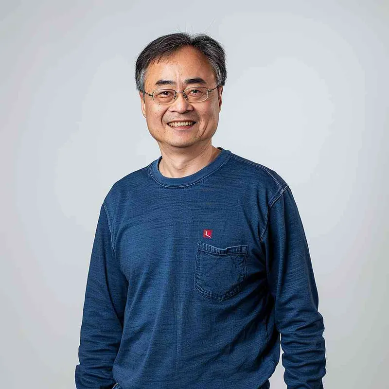 A Chinese man with black hair, wearing a blue long-sleeved shirt and red logo on the chest of Levis jeans is smiling at the camera in a front view. The background color should be white to highlight his facial features. He has short hair and wears glasses that reflect light, giving him a portrait style in the authentic style. His expression conveys confidence as he stands against a clean backdrop. High resolution, professional photograph, and detailed skin texture. Portrait photography. --ar 25:32 - style4部分