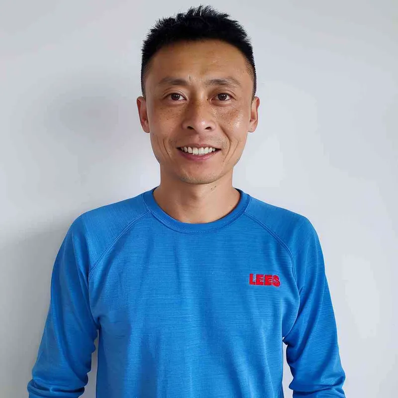 A Chinese man with black hair, wearing a blue long-sleeved shirt with a red logo on the chest is smiling at me from the front view. The background color should be white to highlight his facial features. He has short, dark brown eyes that sparkle slightly when he looks in my direction. His face shows confidence and vitality in the style of Levis. --ar 25:32 - style1部分