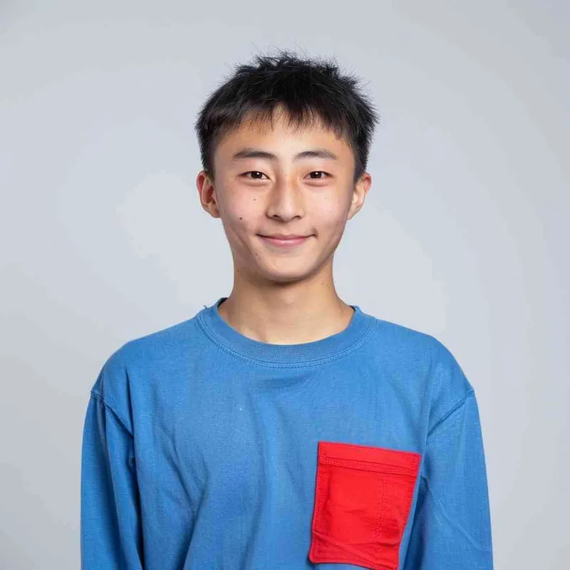 A young Chinese gril with short black hair, wearing a blue long-sleeved shirt with a red pocket on the chest area of his right hand is smiling at the camera. The background color should be white to highlight his face. He has an Asian nose shape, medium skin tone, round eyes, and thin eyebrows. His overall appearance conveys friendliness or confidence. --ar 1:1 --q 1 --v 6.0 - style3部分