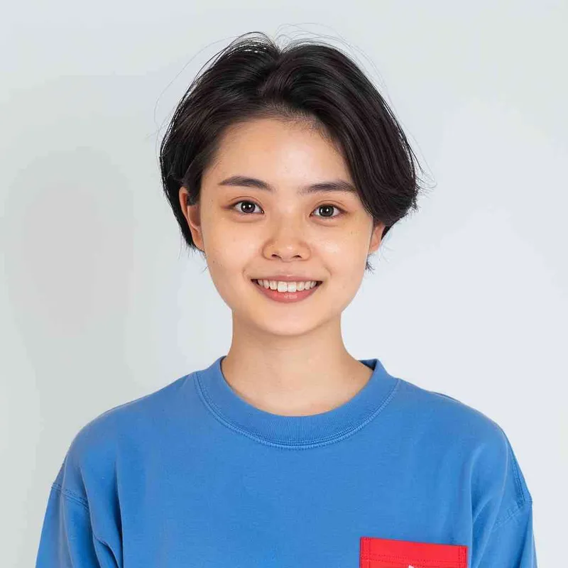 A young Chinese gril with short black hair, wearing a blue long-sleeved shirt with a red pocket on the chest area of his right hand is smiling at the camera. The background color should be white to highlight his face. she has an Asian nose shape, medium skin tone, round eyes, and thin eyebrows. her overall appearance conveys friendliness or confidence. --ar 1:1 --q 1 --v 6.0 - style2部分