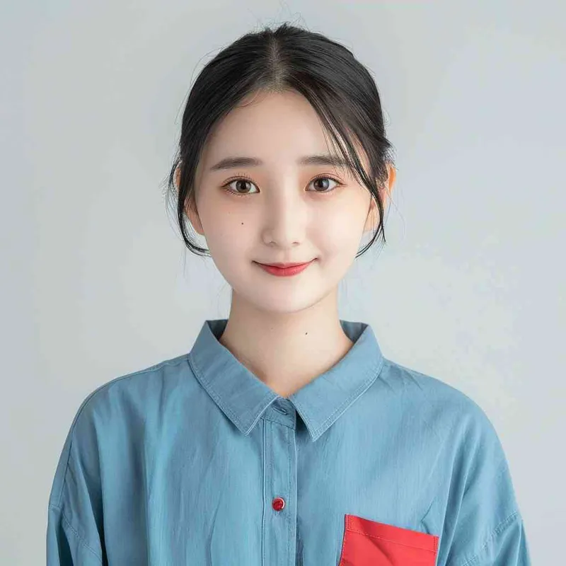 A young Chinese gril with short black hair, wearing a blue long-sleeved shirt with a red pocket on the chest area of his right hand is smiling at the camera. The background color should be white to highlight his face. she has an Asian nose shape, medium skin tone, round eyes, and thin eyebrows. her overall appearance conveys friendliness or confidence. --ar 1:1 --q 1 --v 6.0 - style3部分