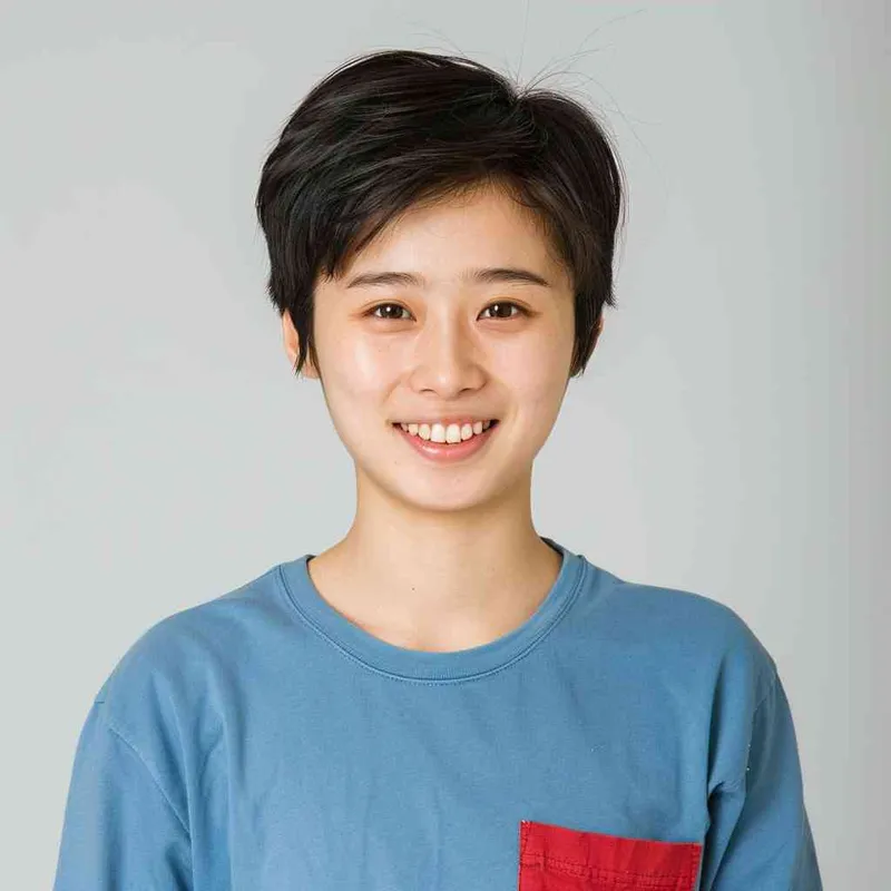 A young Chinese gril with short black hair, wearing a blue long-sleeved shirt with a red pocket on the chest area of his right hand is smiling at the camera. The background color should be white to highlight his face. she has an Asian nose shape, medium skin tone, round eyes, and thin eyebrows. her overall appearance conveys friendliness or confidence. --ar 1:1 --q 1 --v 6.0 - style4部分