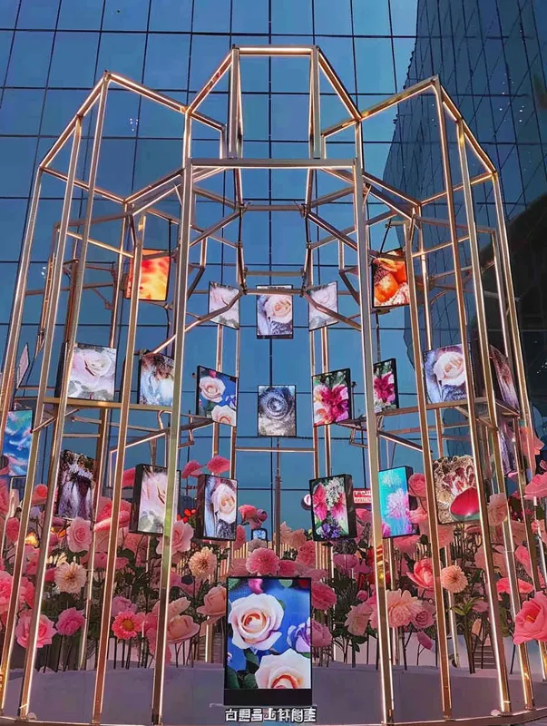 An outdoor digital media art installation, constructed from a golden truss structure, with 30 equally sized LED screens hanging on top, displaying different roses. Front camera, solid color background, lighting effect when the sun is about to set, master photography work, 8k ultra high definition. - style4部分