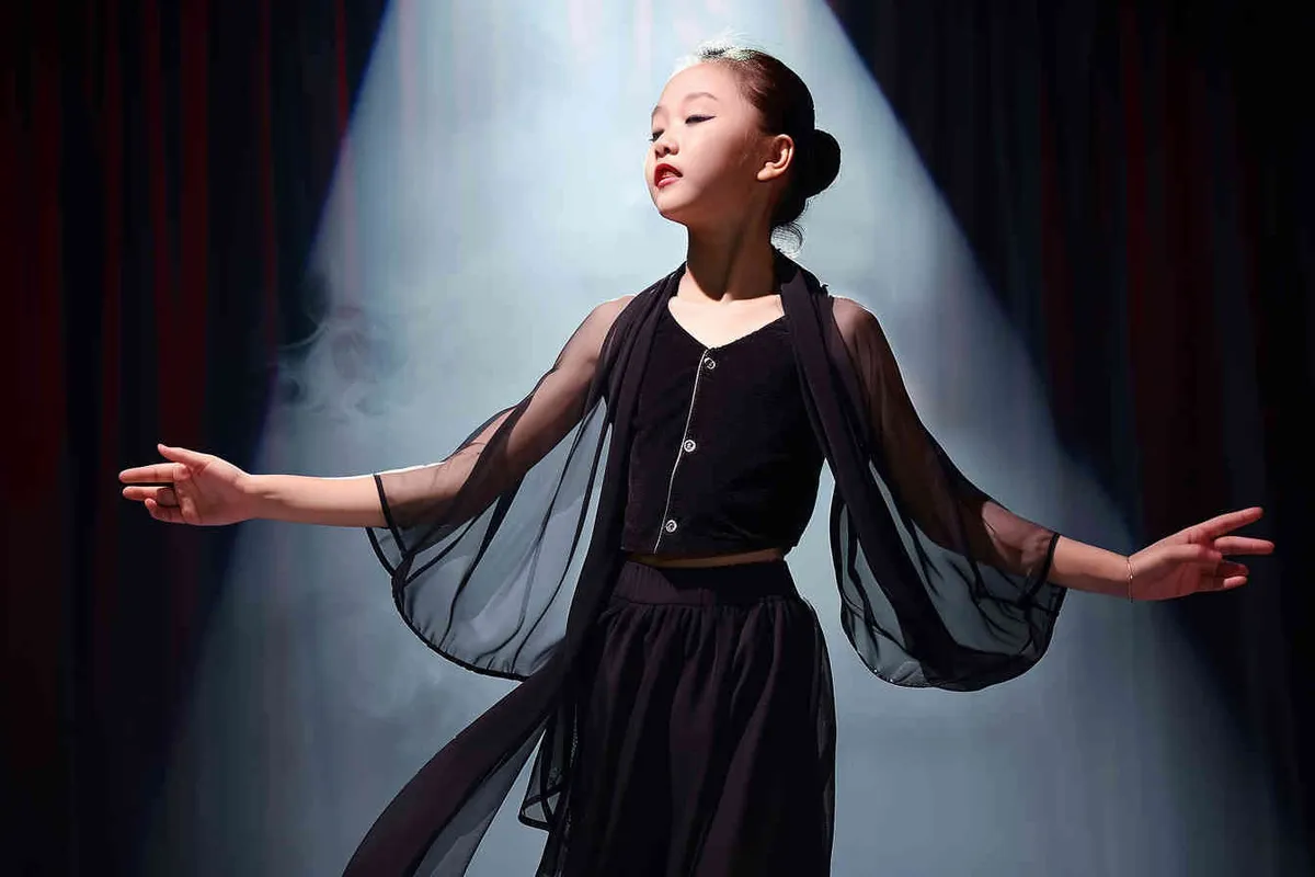 No text!!!!!!!!!!!!!!!!, a 14-year-old Chinese girl, elegantly adorned in a jazz suit, dances with grace on a grand stage, with spot light, face directly into the front. As she captivates the audience, every flawless movement is beautifully captured through the lens of a Canon 85mm f1.2 camera, high quality, high res, 8k, raw, photo reliastic - style1部分